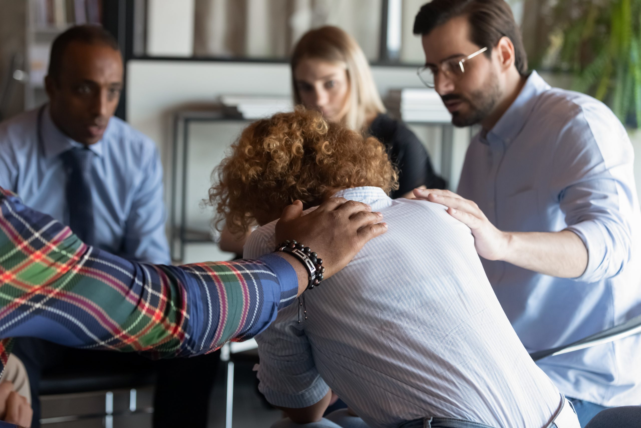 Group of colleagues supporting one emotional employee at work.