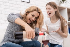 Daughter tries to stop mother from pouring wine.